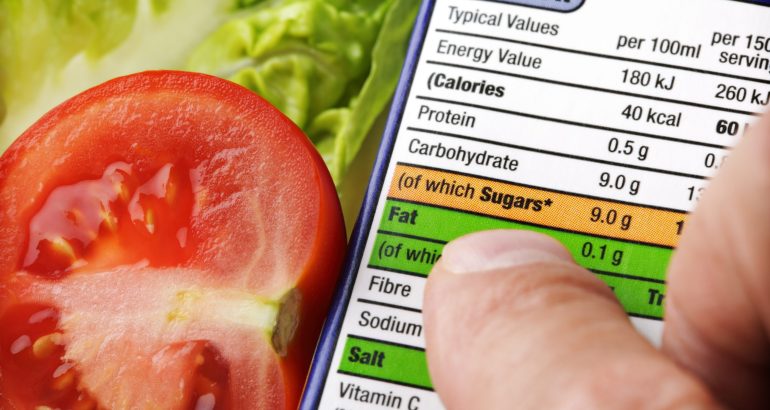 Reading a nutrition label on food packaging with fresh salad background