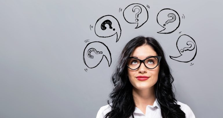 Question marks with speech bubbles with young businesswoman in a thoughtful face