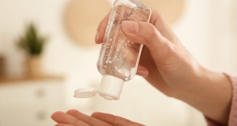 Woman applying antiseptic gel at home, closeup